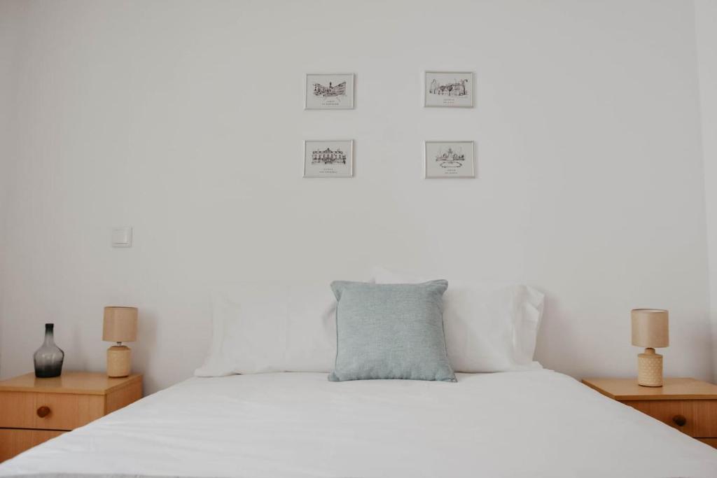 a bedroom with a bed with white sheets and two lamps at Apartamento central, moderno e luminoso - Self check in in Coimbra