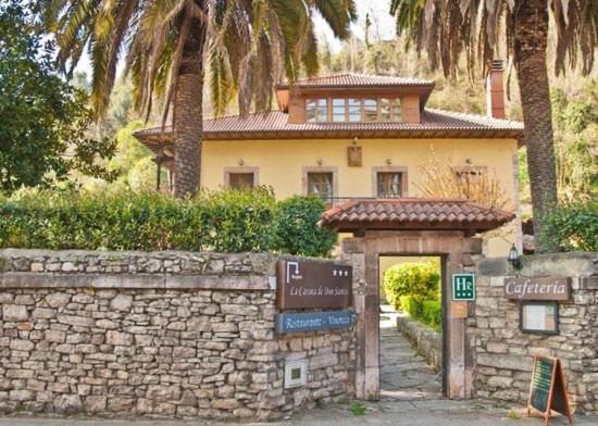 a house with a stone wall and a sign in front at La Casona de Don Santos in Proaza