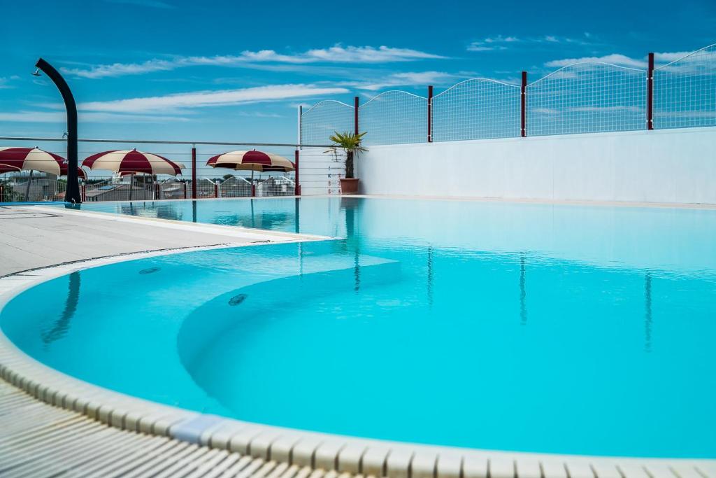 a swimming pool with blue water and a fence at Hotel Vienna in Lignano Sabbiadoro