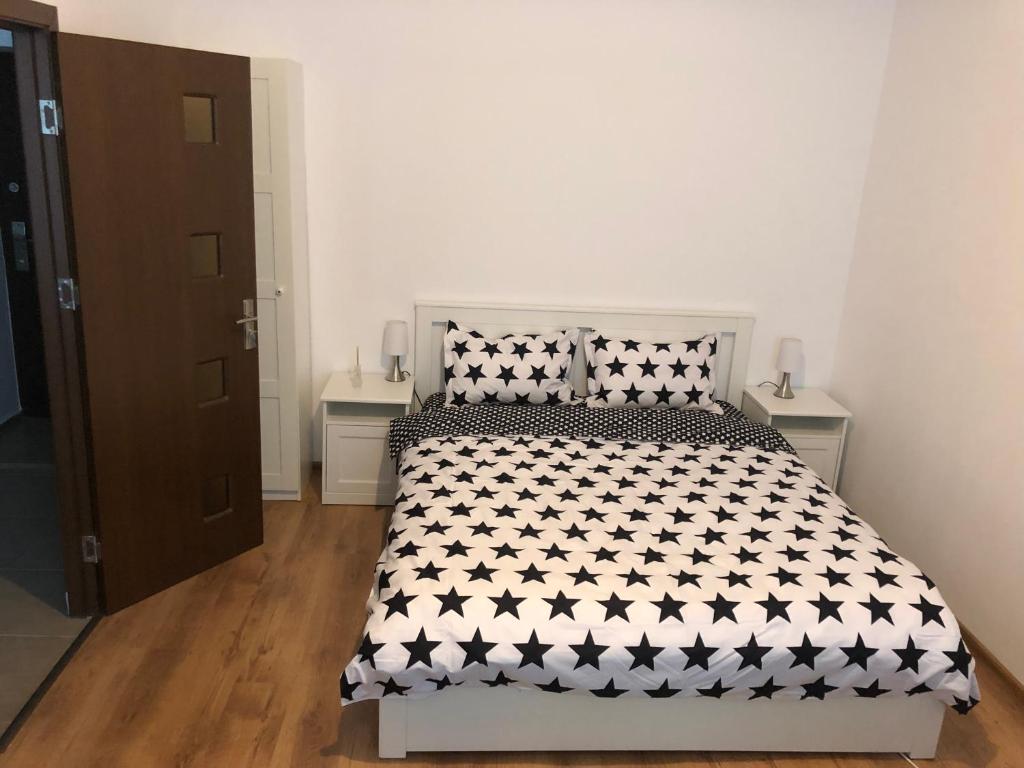 Schlafzimmer mit einem Bett mit einer schwarzen und weißen Bettdecke in der Unterkunft Poppys Apartment in Arad