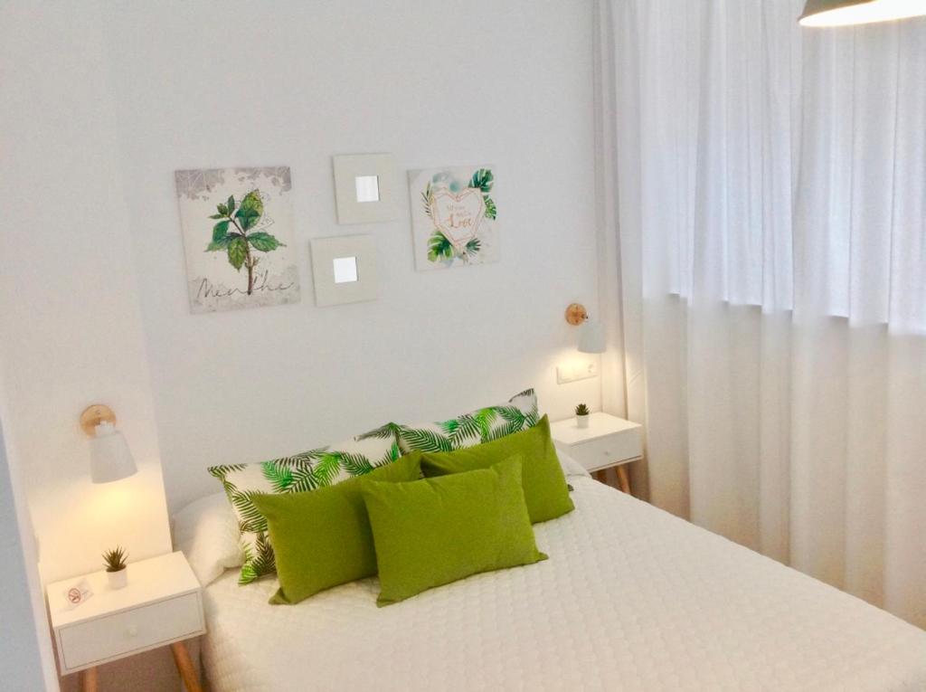 - une chambre blanche avec des oreillers verts sur un lit dans l'établissement Apartamento Don Miguel Playa, à Fuengirola