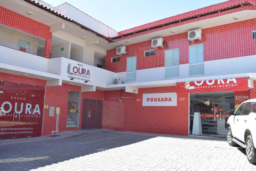 un coche blanco estacionado frente a un edificio en Loura Pousada, en Sobral