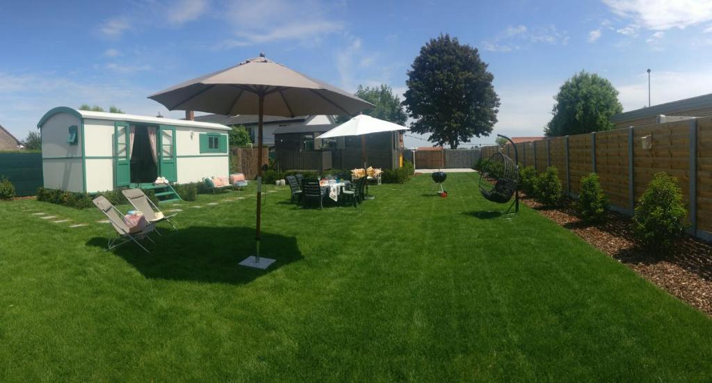 a yard with an umbrella and chairs and a house at Jardin Jannik in Watou