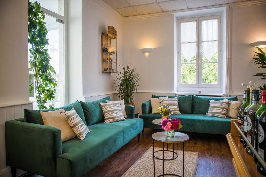 a living room with two green couches and a table at Hostellerie du Parc in Cambo-les-Bains