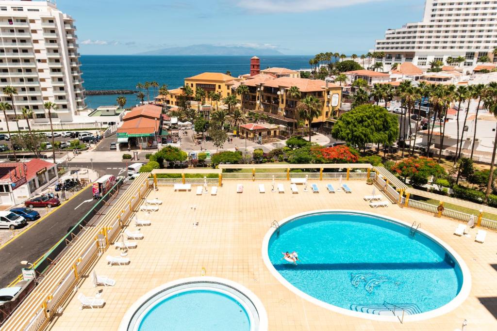 una vista aérea de una piscina con sillas y el océano en HomeForGuest BEACH APT WITH SEA VIEW & POOL, 50 STEPS TO THE SEA en Playa Fañabe