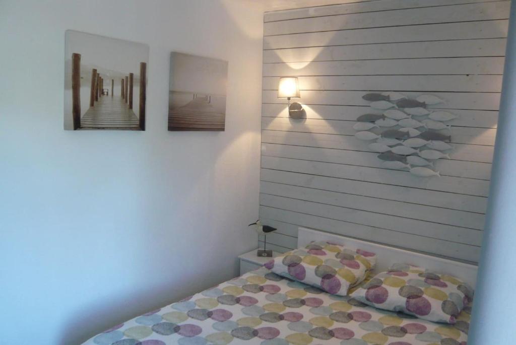 GITE BORD DE MER في Bernières-sur-Mer: غرفة نوم بسرير وصورتين على الحائط