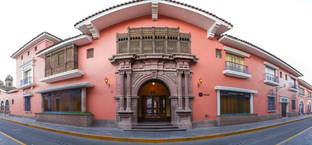 a pink building with an archway on a street at DM Hoteles Ayacucho in Ayacucho