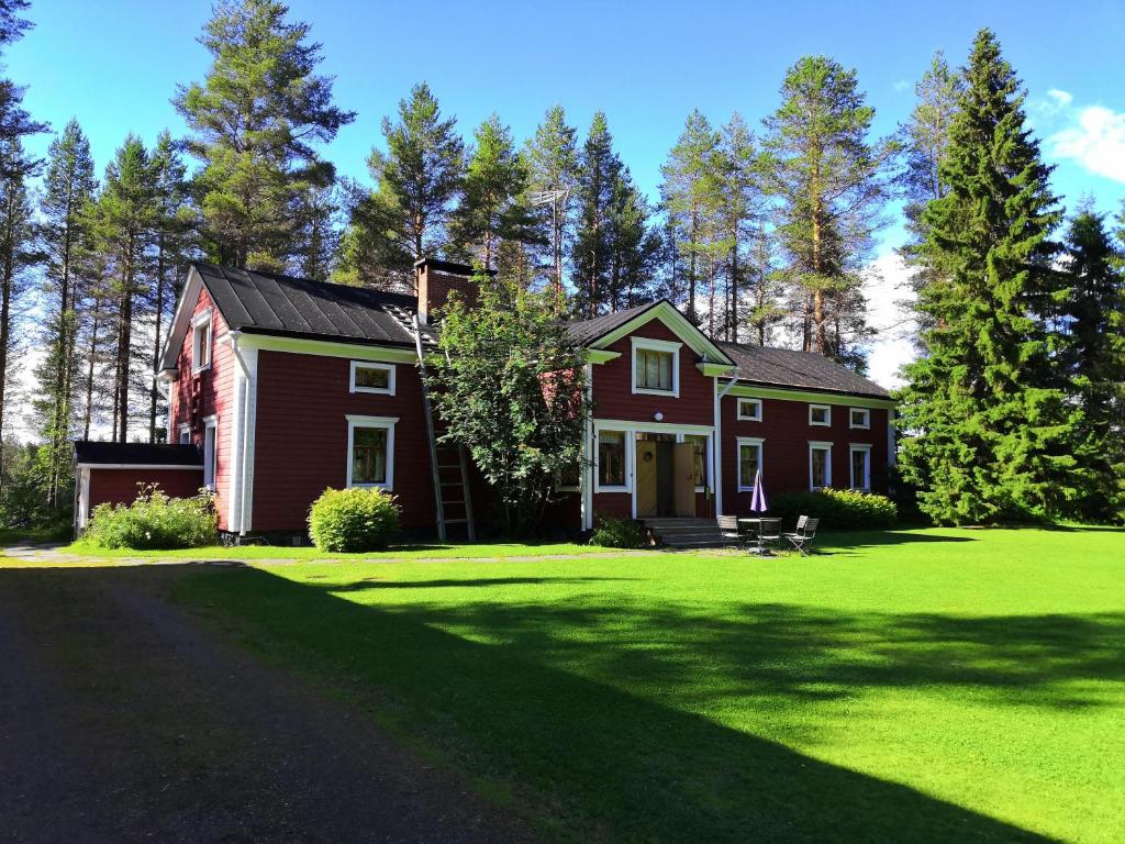 a red house on a green yard with trees at Rehto in Rovaniemi