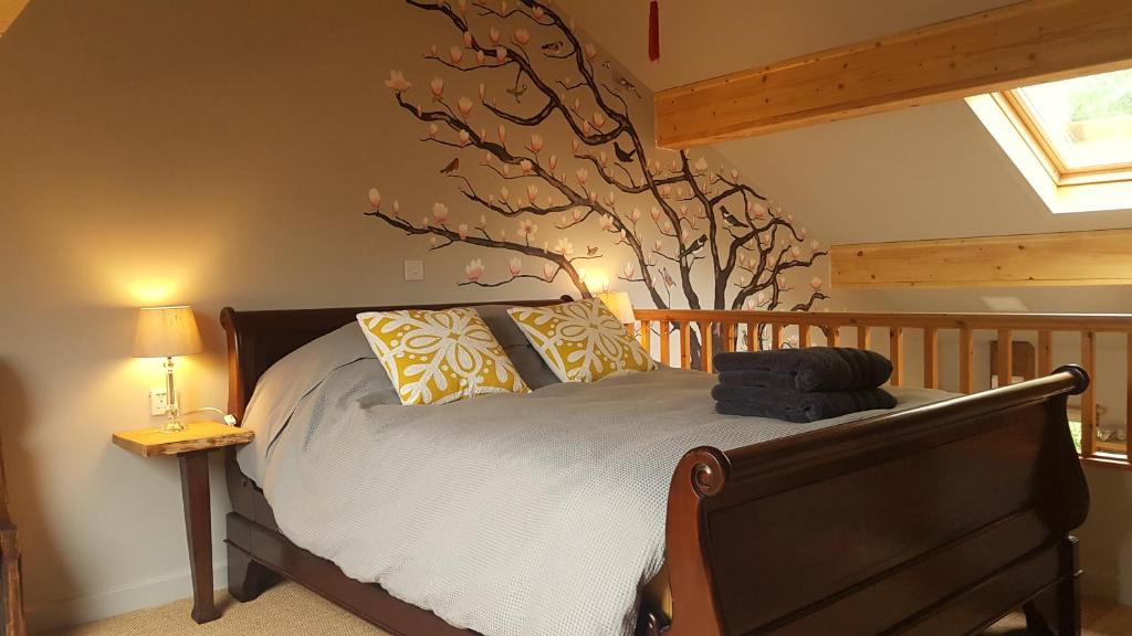 a bedroom with a bed with a tree on the wall at Wimpenny Place in Holmfirth