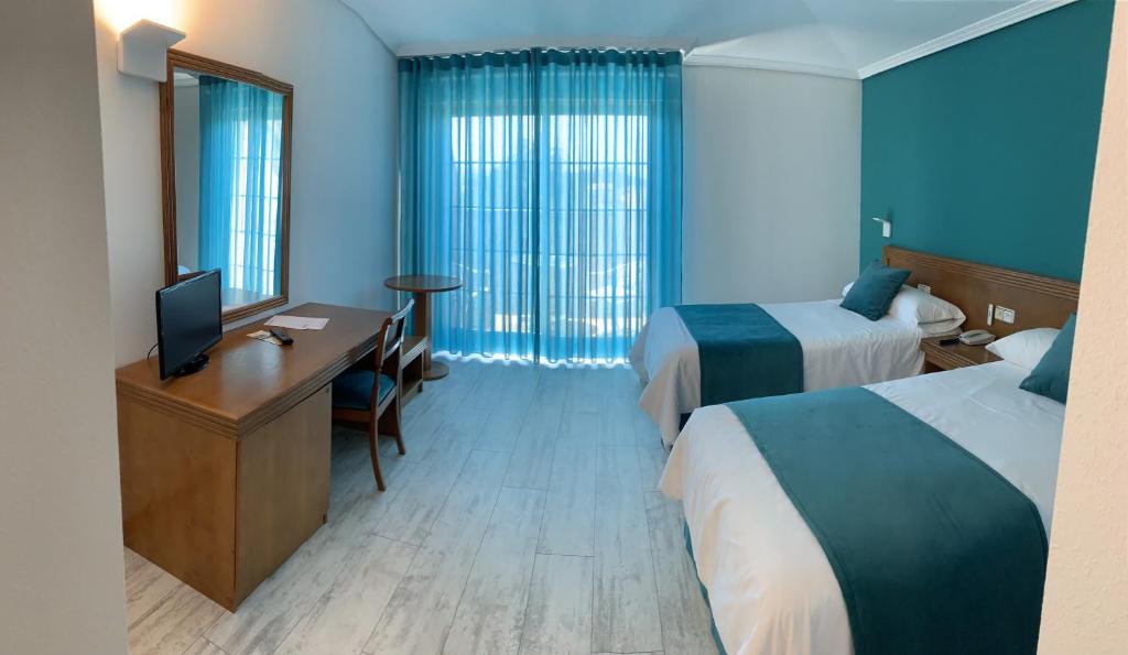 TomiñoにあるNueva Colinaのベッド2台、デスク、テレビが備わるホテルルームです。