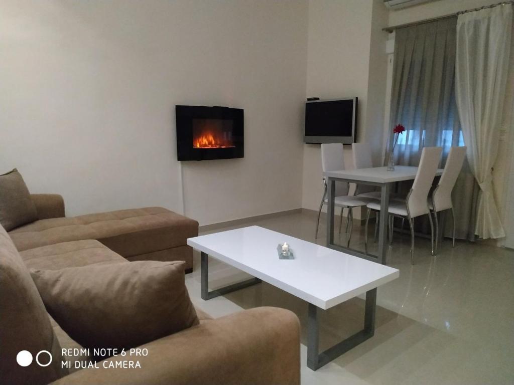 ein Wohnzimmer mit einem Sofa und einem Tisch mit einem Kamin in der Unterkunft LAVIM Apartments 2 in Sykia