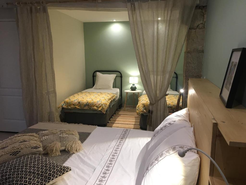 a bedroom with two beds and a flat screen tv at Les 3 échoppes in Chargé