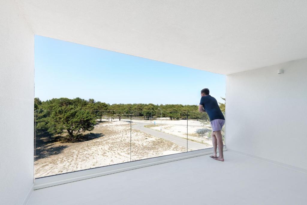 a man standing on the edge of a white room looking at a window at Hothel in Hel