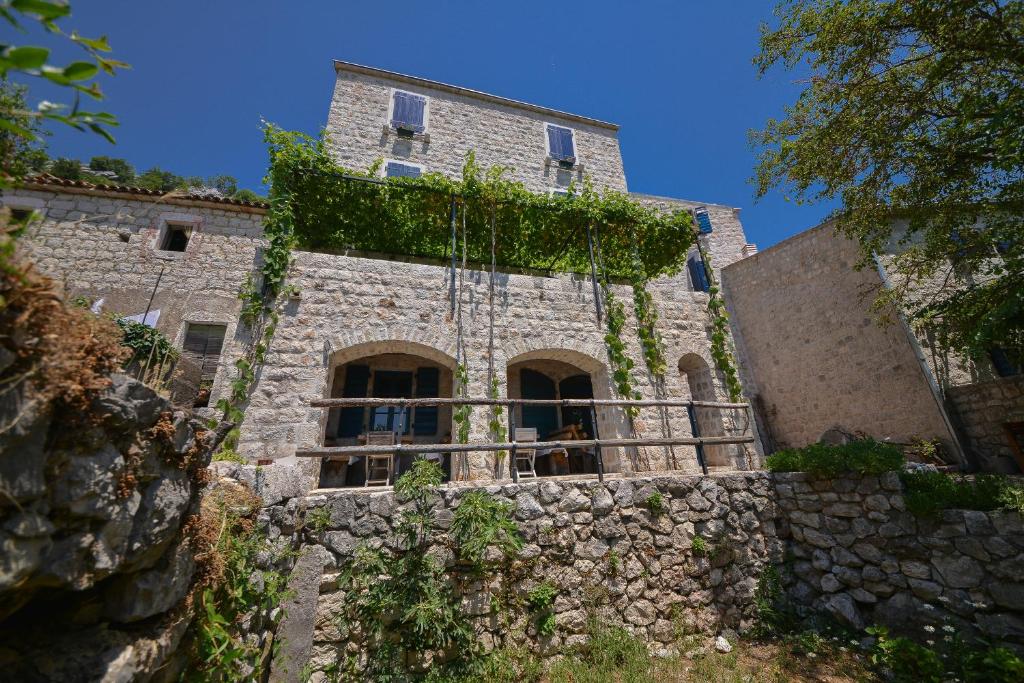 un viejo edificio de piedra con hiedra. en B&B Apart Hotel Paštrovski Konak, en Sveti Stefan