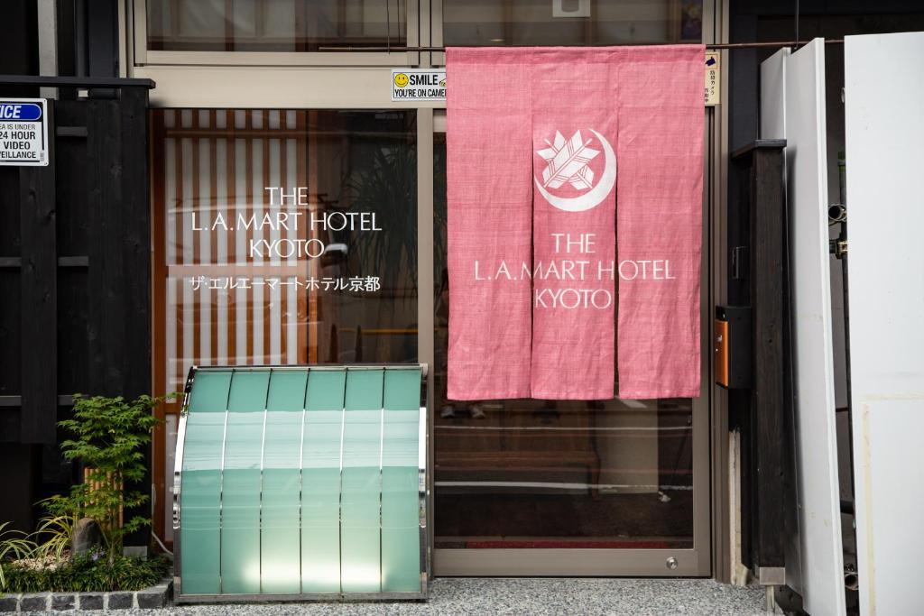 THE L.A. MART HOTEL KYOTO في كيوتو: باب امام مبنى عليه لافته ورديه وبيضاء