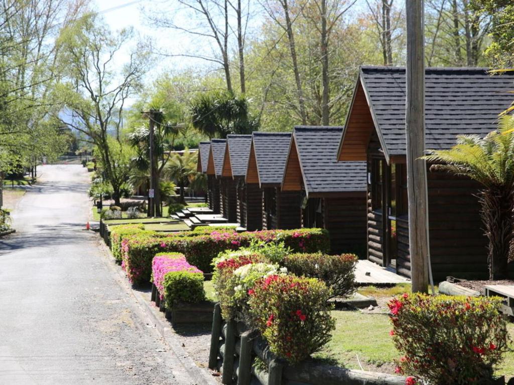 rząd krzaków i kwiatów przed budynkiem w obiekcie Rotorua Thermal Holiday Park w mieście Rotorua