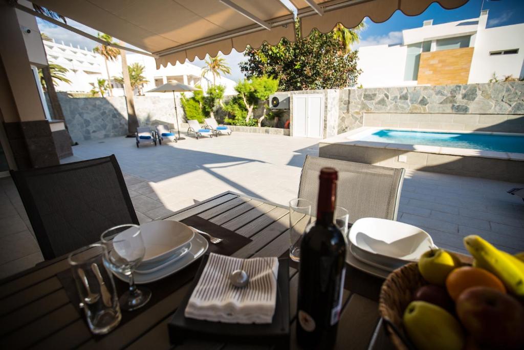 einen Tisch mit einer Flasche Wein und einem Obstkorb in der Unterkunft Villa Jandia Modern new apartment Morro Jable Private heated pool big terrace and parking in Morro del Jable