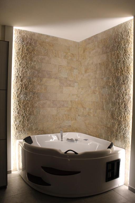 una vasca da bagno bianca in una stanza con parete di Villa Martina Luxury Rooms a Desenzano del Garda