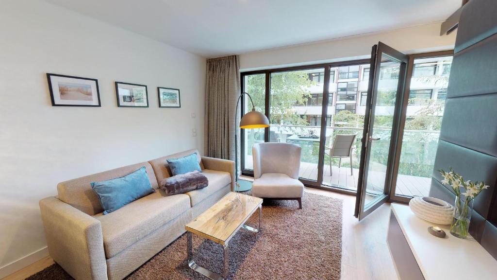 een woonkamer met een bank en een stoel bij White Pearl Apartment 1.13 in Timmendorfer Strand