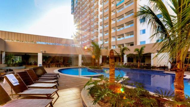 um hotel com piscina e espreguiçadeiras e um edifício em Apartamento em Resort de Olimpia em Olímpia
