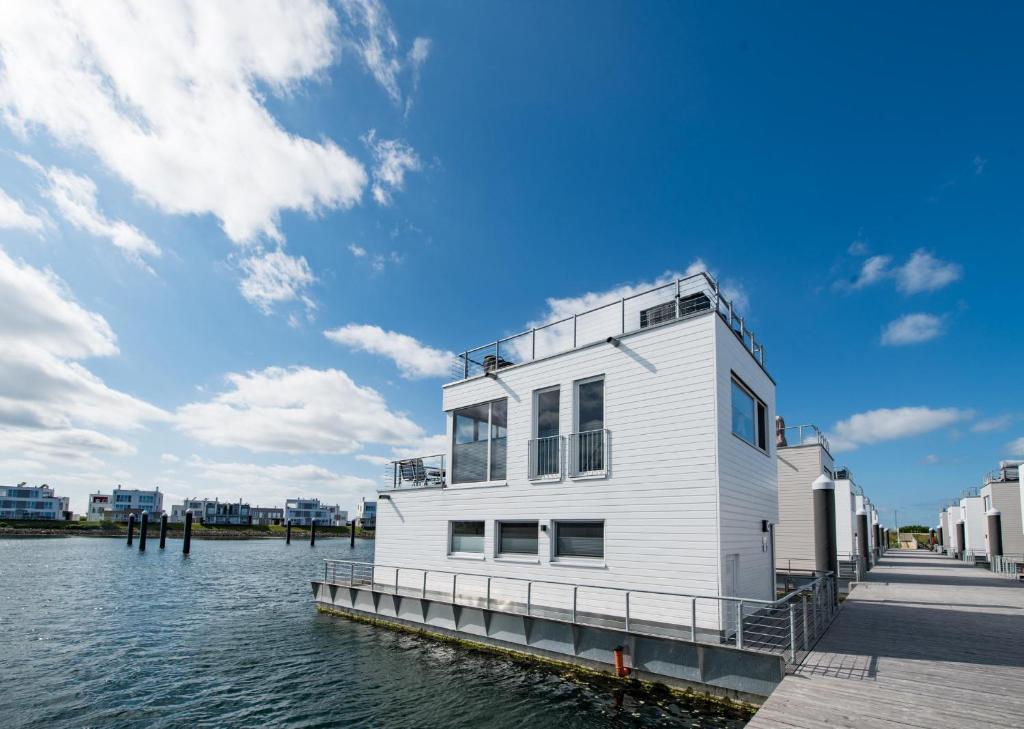 ein weißes Gebäude auf einer Anlegestelle am Wasser in der Unterkunft Schwimmendes Haus Marina Rainbow in Olpenitz