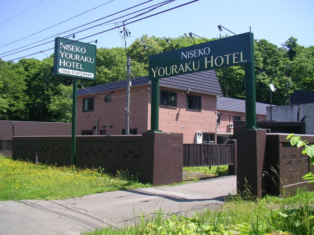 dos señales para un hotel frente a un edificio en Niseko Youraku Hotel en Niseko