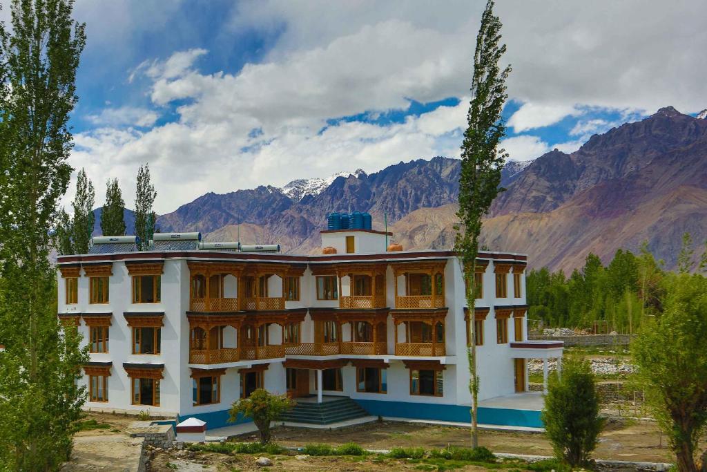 a large building with mountains in the background at Hunder Residency in Leh