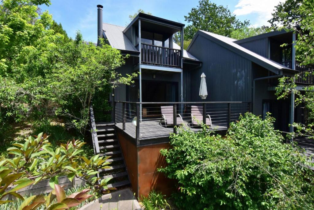 a black house with a deck and stairs at Cloudsong Chalet 3 Close to the village centre in Kangaroo Valley