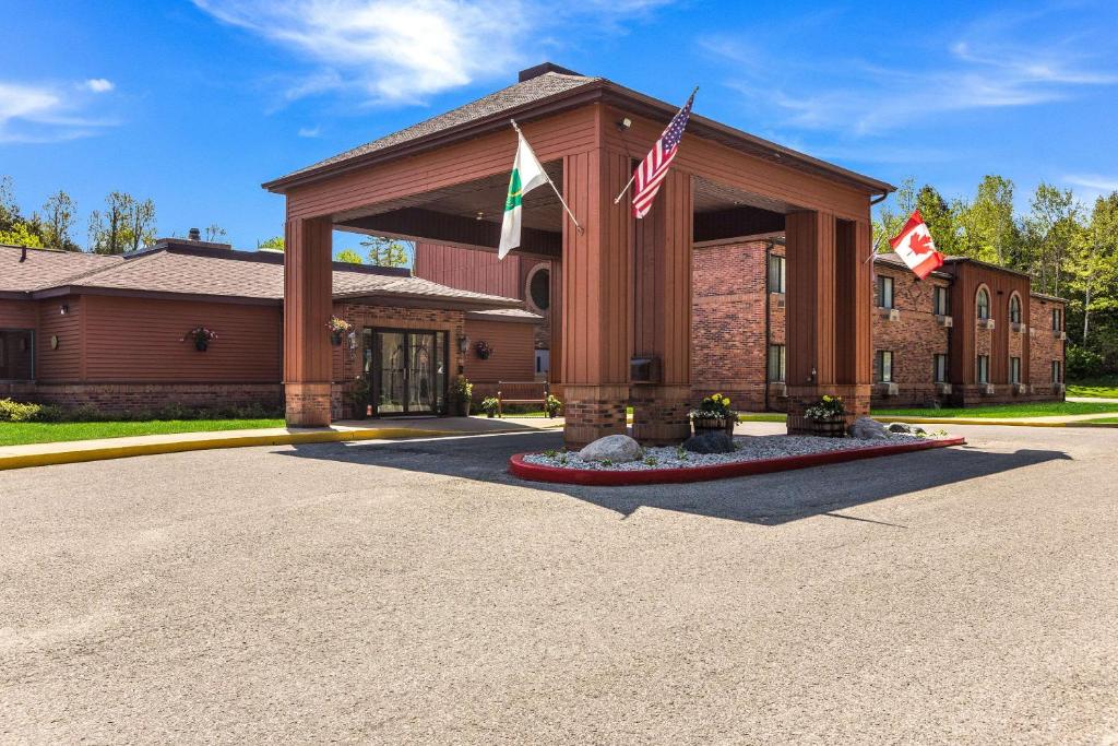 un bâtiment avec deux drapeaux devant lui dans l'établissement Quality Inn Petoskey-Harbor Springs, à Petoskey