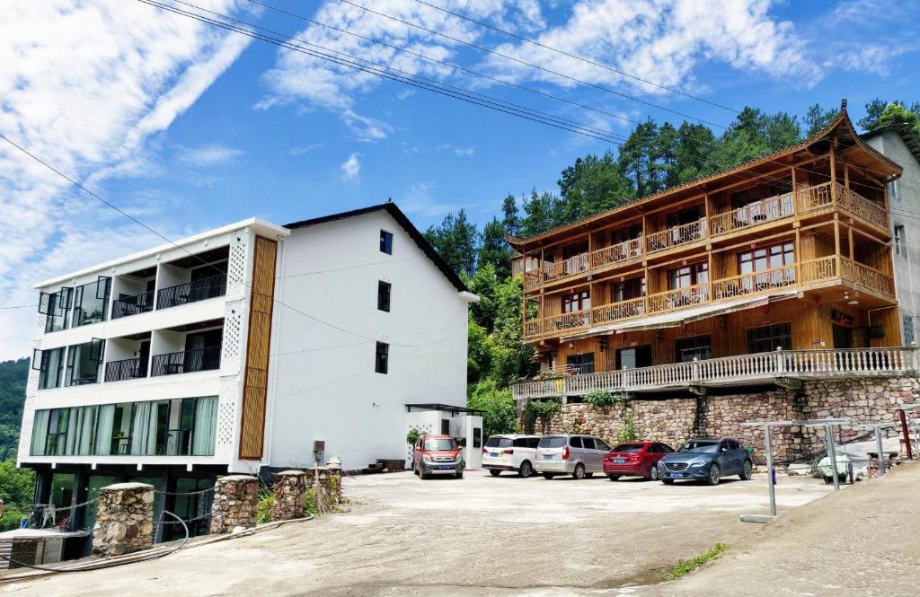 two buildings with cars parked in a parking lot at Whispering Mountains Boutique Hotel in Zhangjiajie