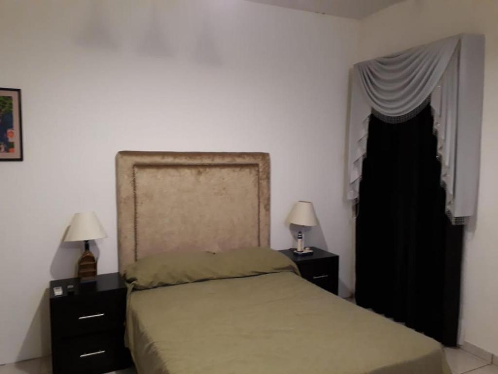 um quarto com uma cama e duas mesas de cabeceira e uma janela em Martha´s HOUSE em Culiacán