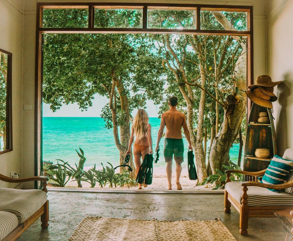 a man and woman standing in a room looking at the ocean at Whispering Palms - Absolute Beachfront Villas in Port Vila