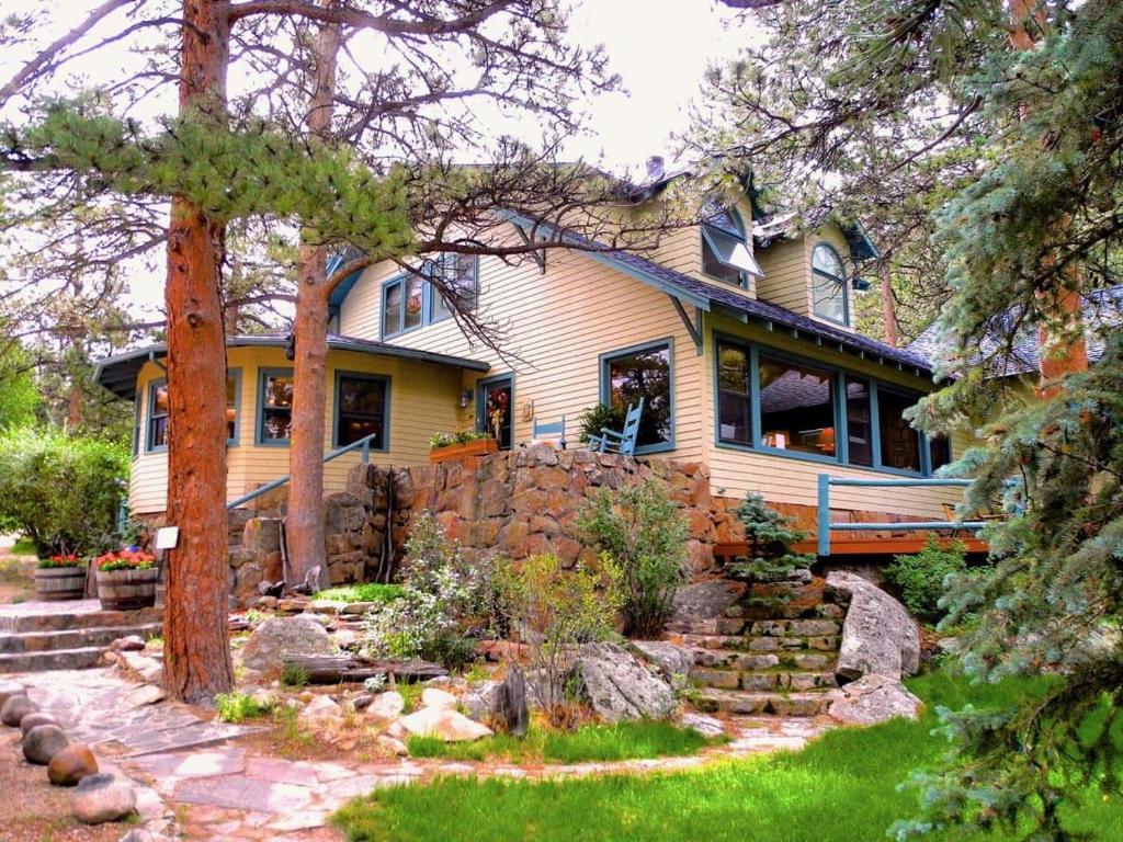 una casa gialla con un muro di pietra di Riversong Inn Retreat a Estes Park