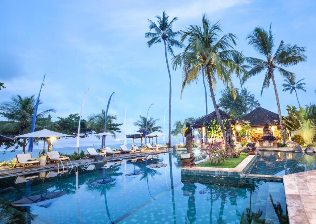 a swimming pool at a resort with palm trees at Puri Bagus Candidasa in Candidasa