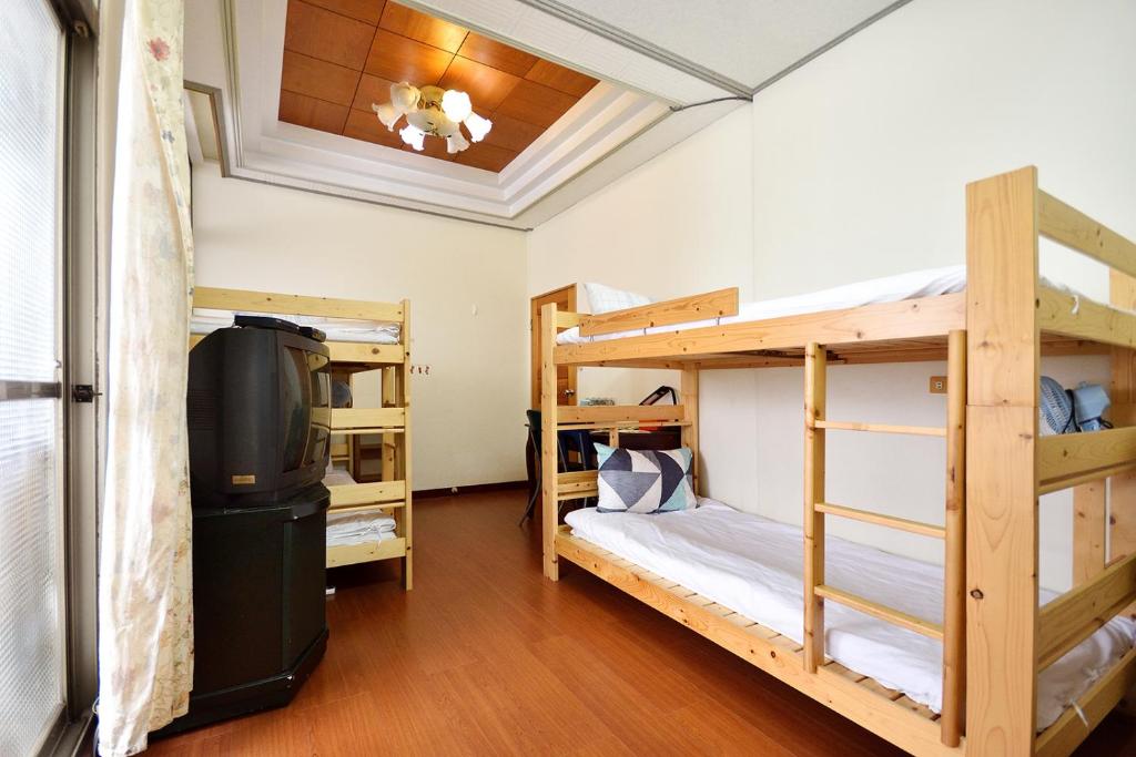 a room with three bunk beds and a flat screen tv at Yiwa Homestay in Taitung City