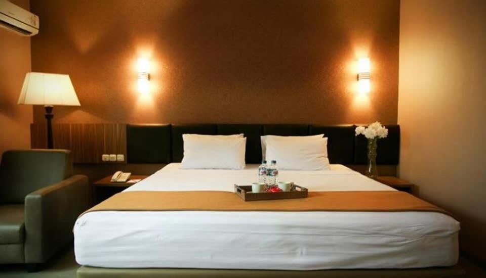 ein Hotelzimmer mit einem großen Bett und einem Tablett darauf in der Unterkunft Raden Wijaya Hotel & Convention in Mojokerto