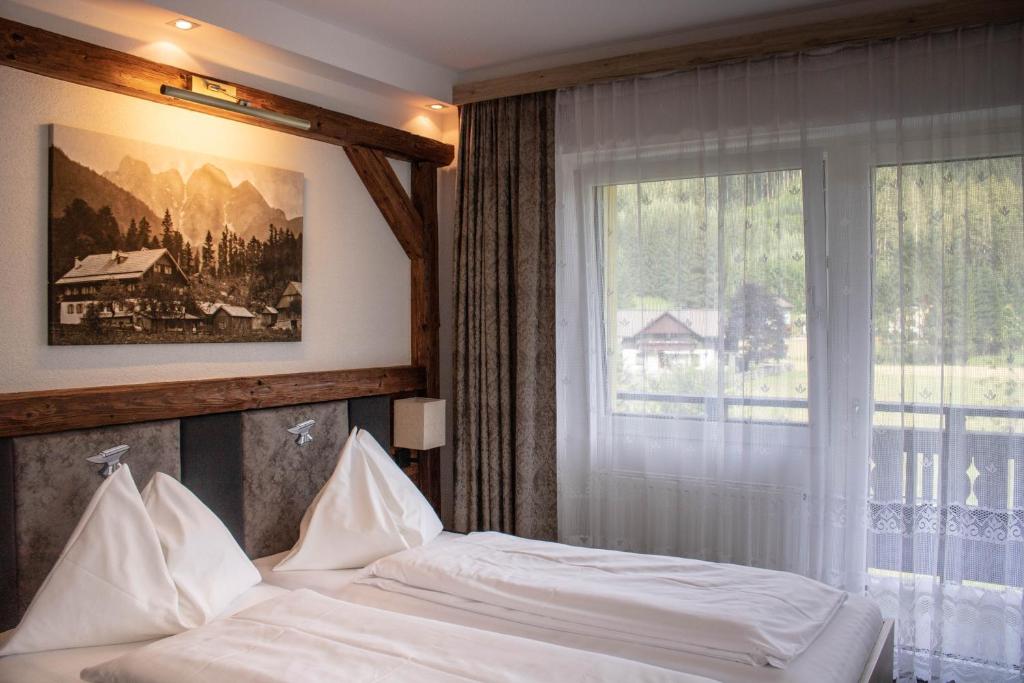 a bedroom with a bed and a large window at Gasthof Gosauschmied in Gosau