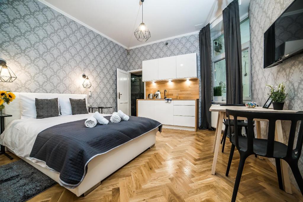 a bedroom with a large bed and a kitchen at Cracovia Wawel Apartments in Kraków