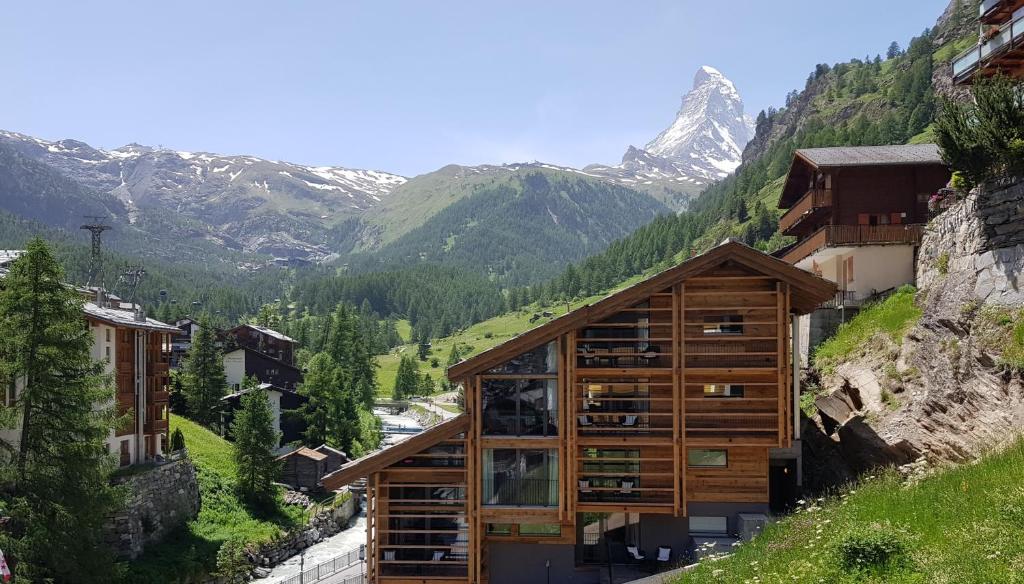 un edificio en una colina con montañas en el fondo en Haus Sonnheim, en Zermatt