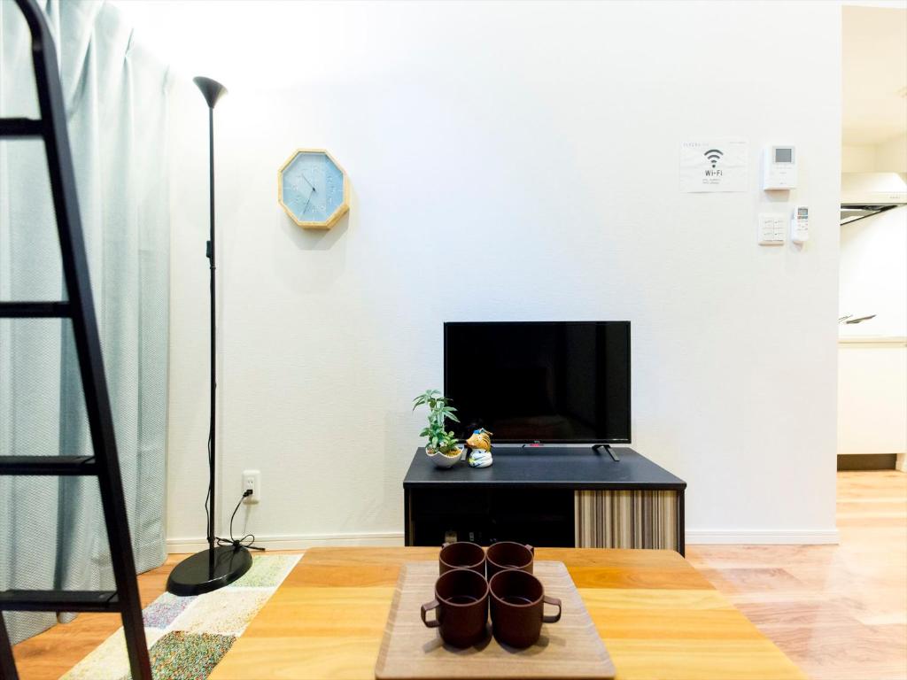 a living room with a tv and a coffee table at TRIP POD HIGASHI-HIE in Fukuoka