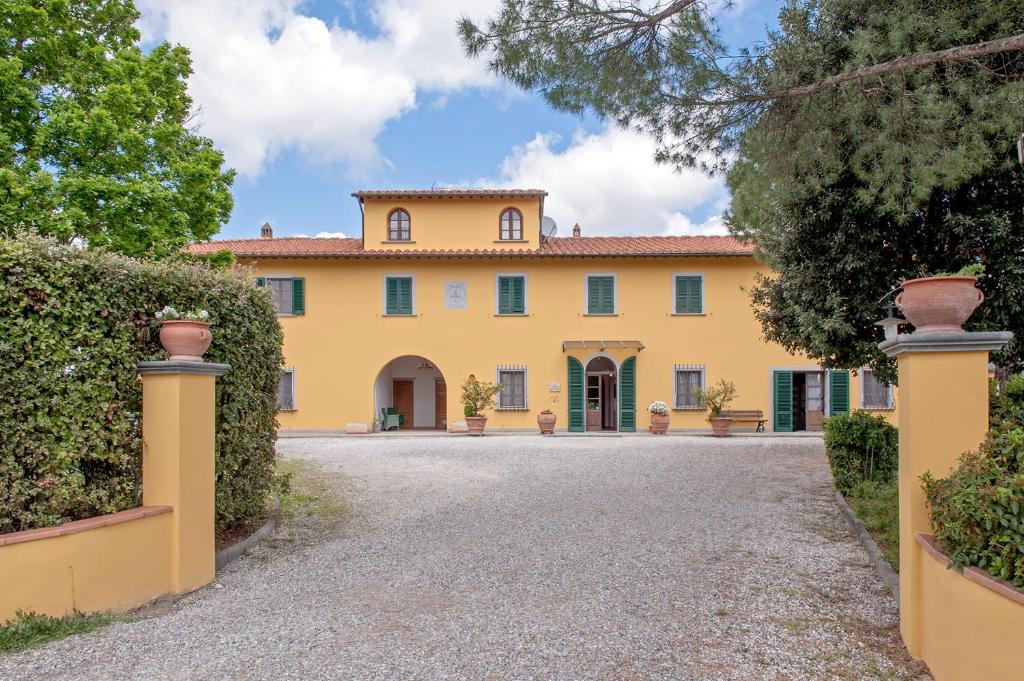 an exterior view of a large yellow house with a driveway at Agriturismo Isola Verde in Cerreto Guidi