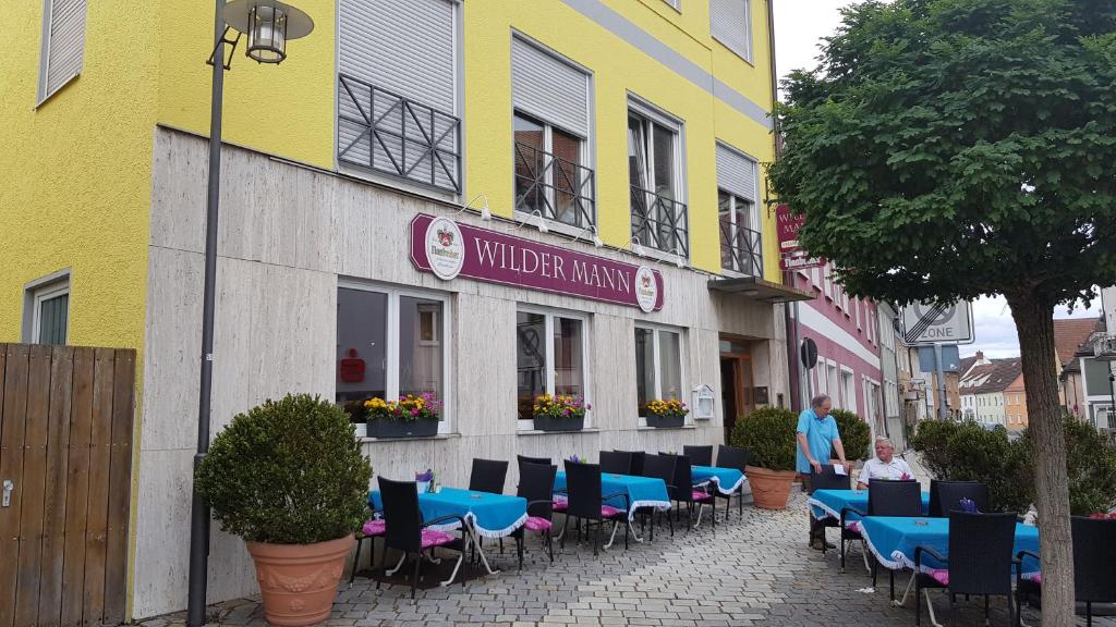Hotel-Gasthof Wilder Mann في Pfreimd: مطعم بطاولات زرقاء وكراسي على شارع