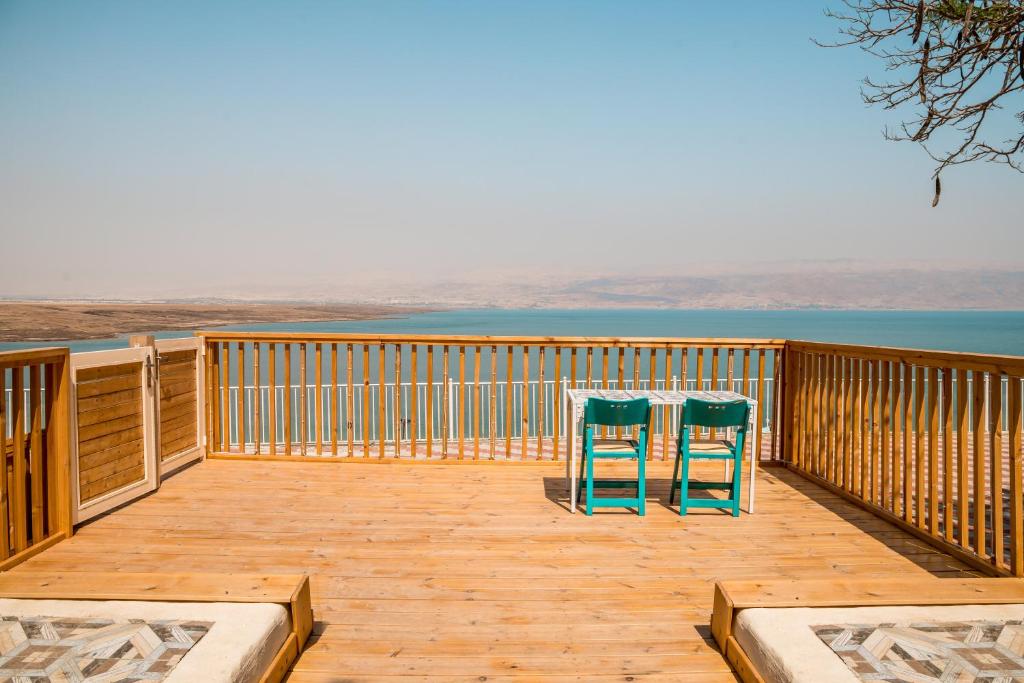 two chairs sitting on a wooden deck with the view of the ocean at The Dream Compound- by Biankini in Kalia