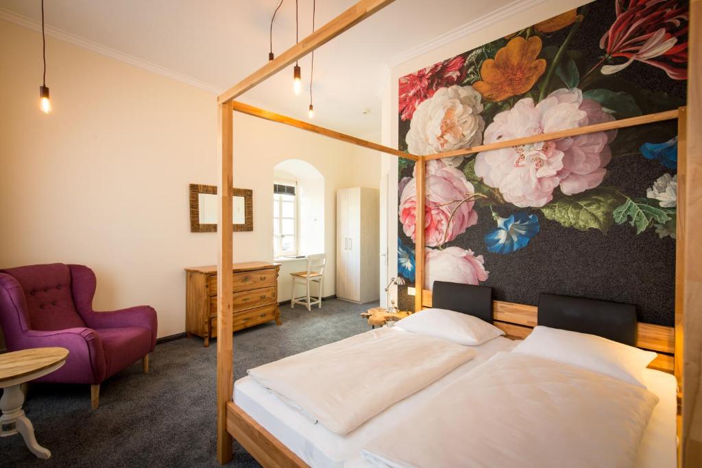 una camera con letto a baldacchino e un dipinto di fiori di Hotel Deutschherrenhof a Zeltingen-Rachtig
