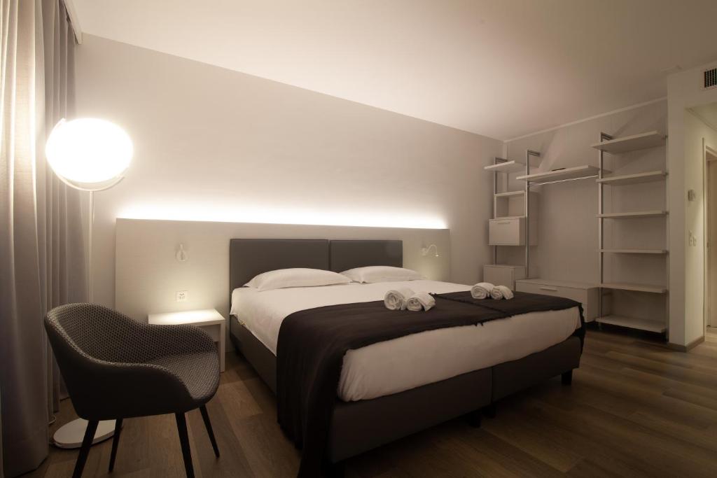 a bedroom with a large bed and a chair at Hotel Albergo Milano in Mendrisio