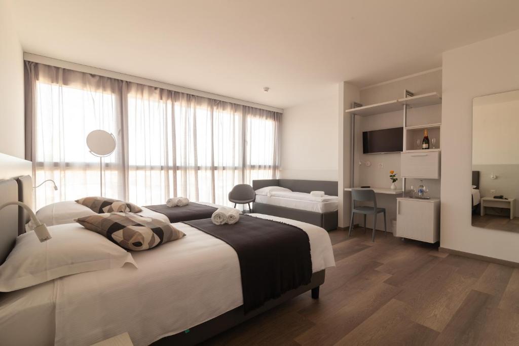 a white bedroom with a large bed and a desk at Hotel Albergo Milano in Mendrisio
