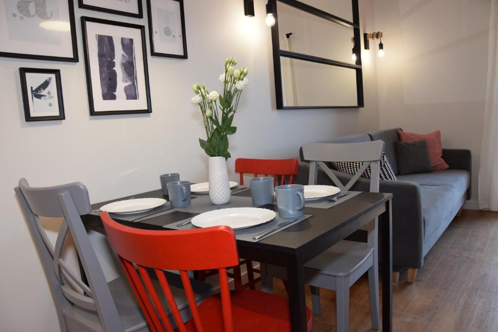 a dining room with a table with chairs and a couch at VerrAri Apartaments in Łeba