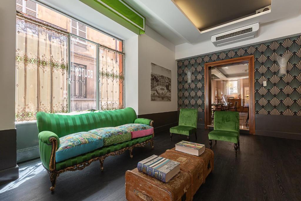 a living room with a green couch and two green chairs at Hotel Button in Parma