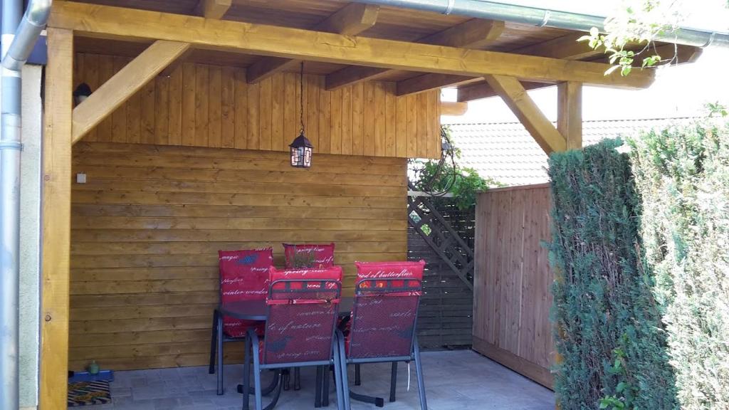 un patio con sedie rosse e pergolato in legno di Ferienwohnung Kretzschmar a Kirnitzschtal