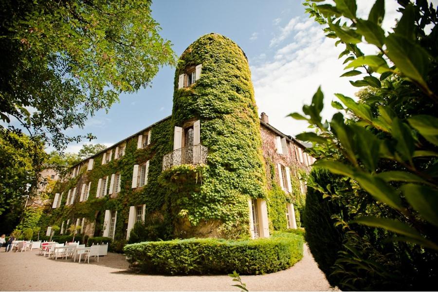 un edificio cubierto de hiedra verde junto a un edificio en Chateau d'Ayres - Hôtel & Spa, en Meyrueis